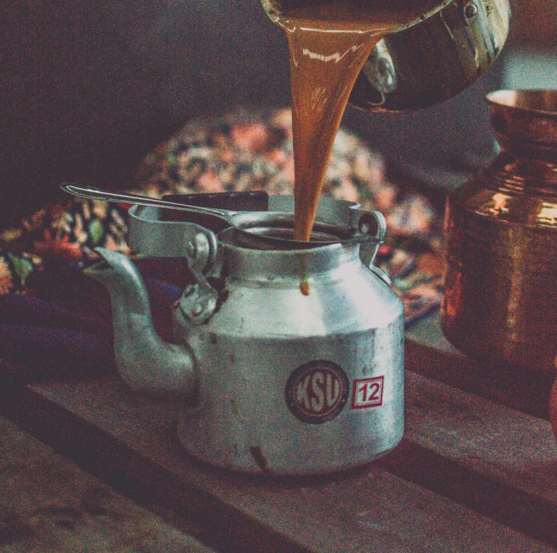 A chai kettle with chai being poured in it